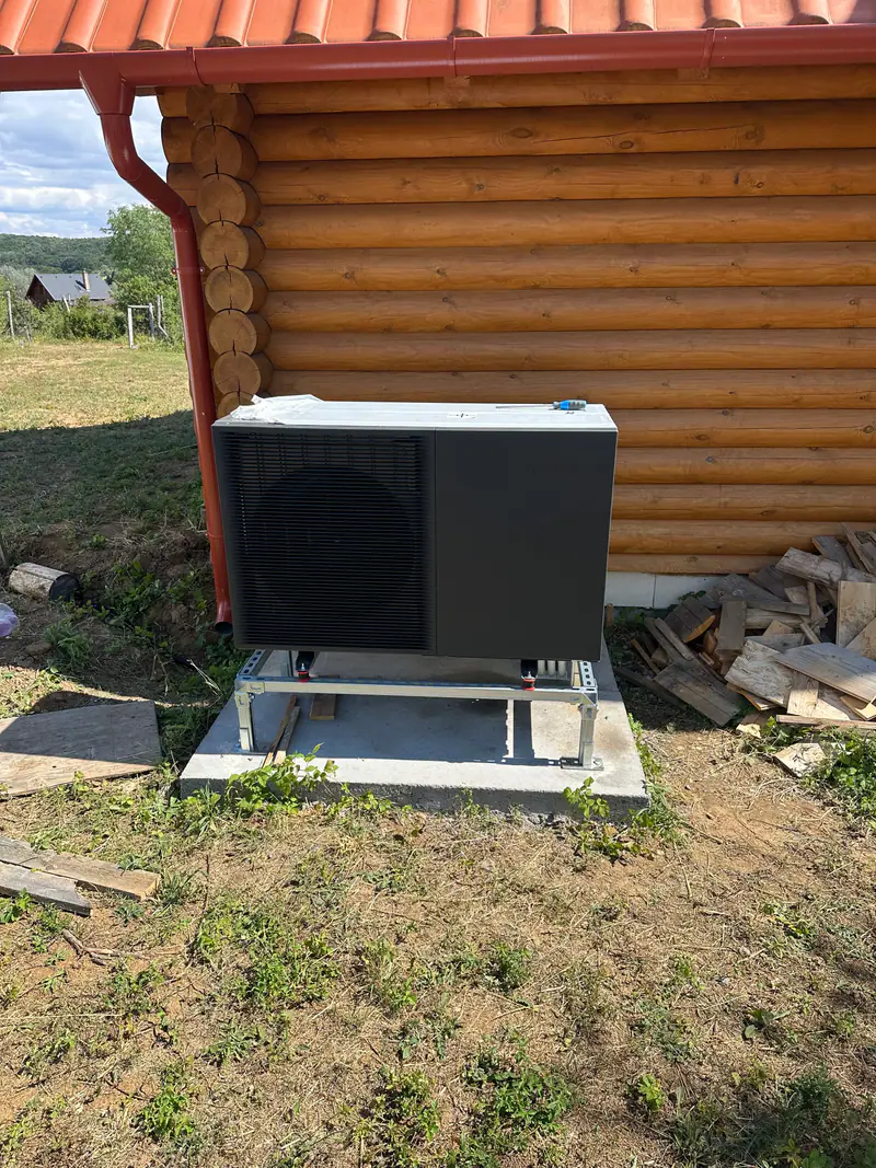 Monoblokkos hőszivattyú acél állványon egy rönkház mellett – Alsópetény