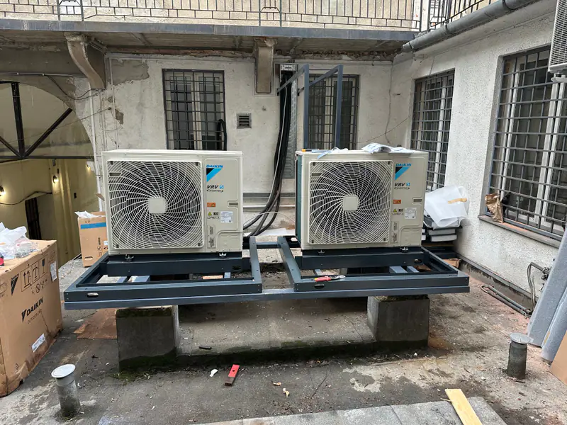 Két Daikin kültéri egység acél kereten egy régi bérház belső udvarán, szerelés közben – budapesti bankfiók