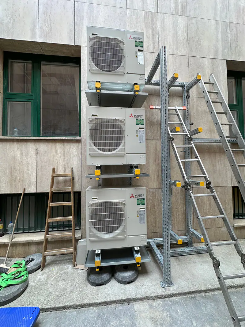 Három Mitsubishi Electric kültéri egység egymás fölött acél állványon, egy konyhai légkezelő géphez – Országgyűlés Irodaháza, Budapest