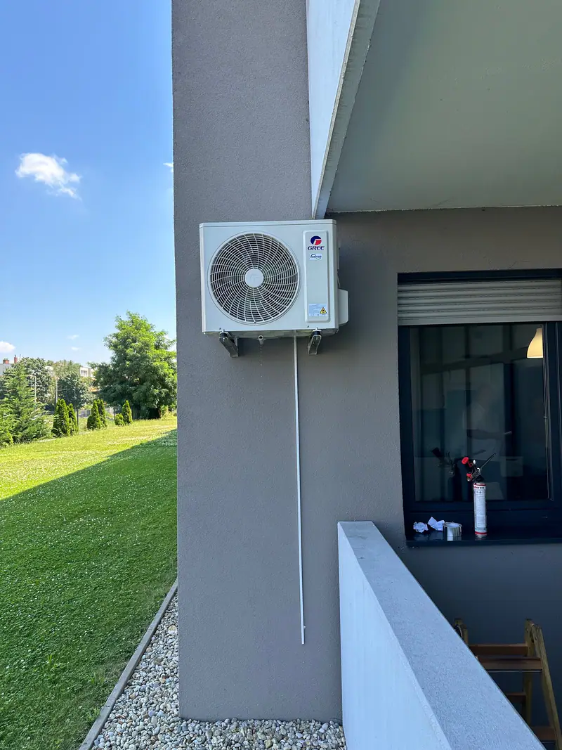 Split klíma kültéri egysége falikonzolon egy ház sarkán